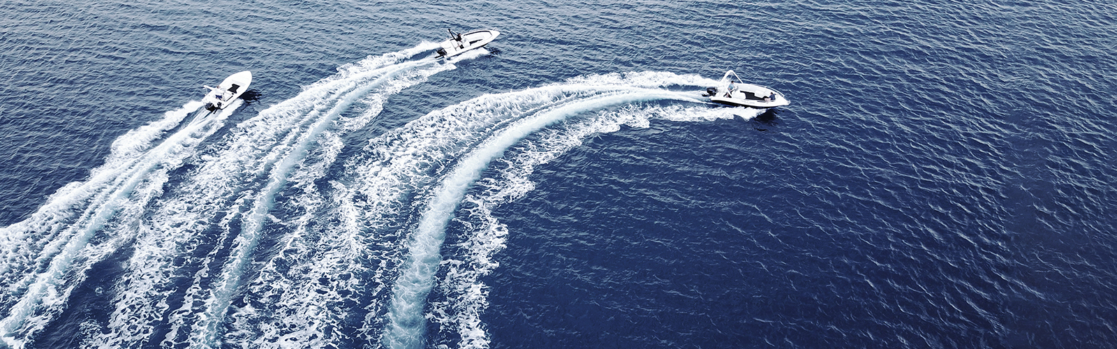 Three boats speeding in the open ocean