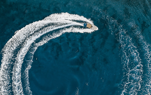 Speed boat in mediterranean sea making a cyrcle from bubbles, aerial view