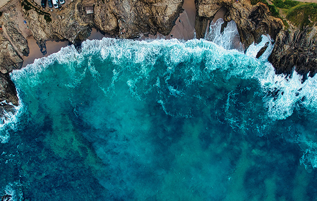 Aerial View of Turquoise Waves Crashing on Rocky Coastline at Little Fistral Beach, Newquay, UK