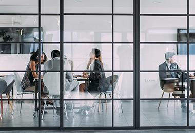 Financial professionals sitting at a table in a glass conference room