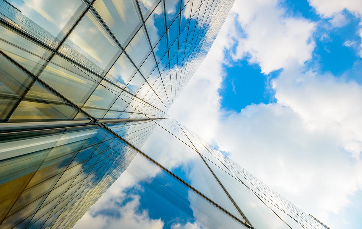 Looking up at a glass building facade and blue sky
