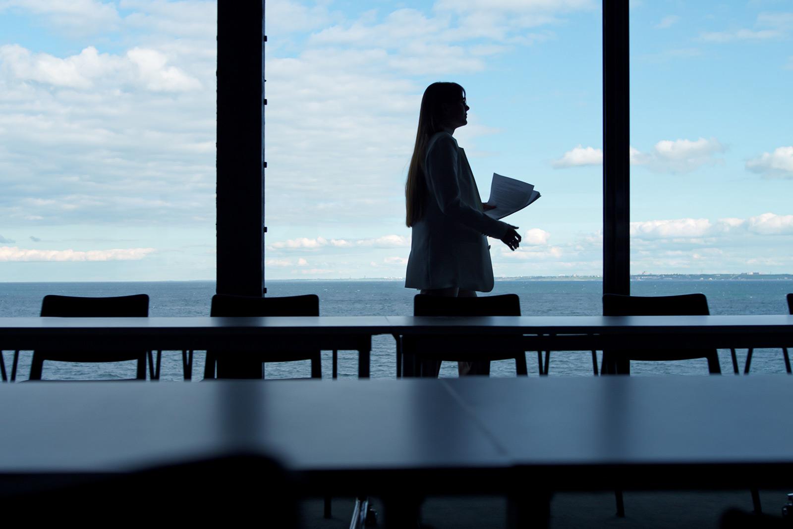 Woman in an empty meeting room with a view of a body of water