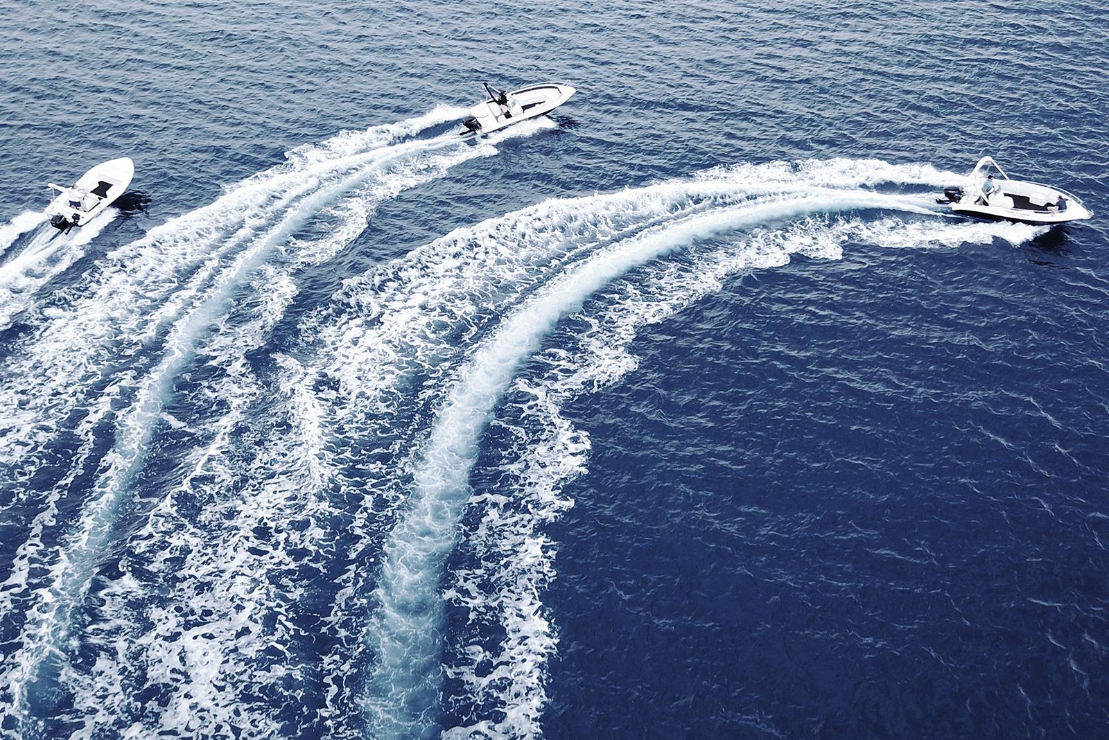 Three boats speeding in the open ocean cropped