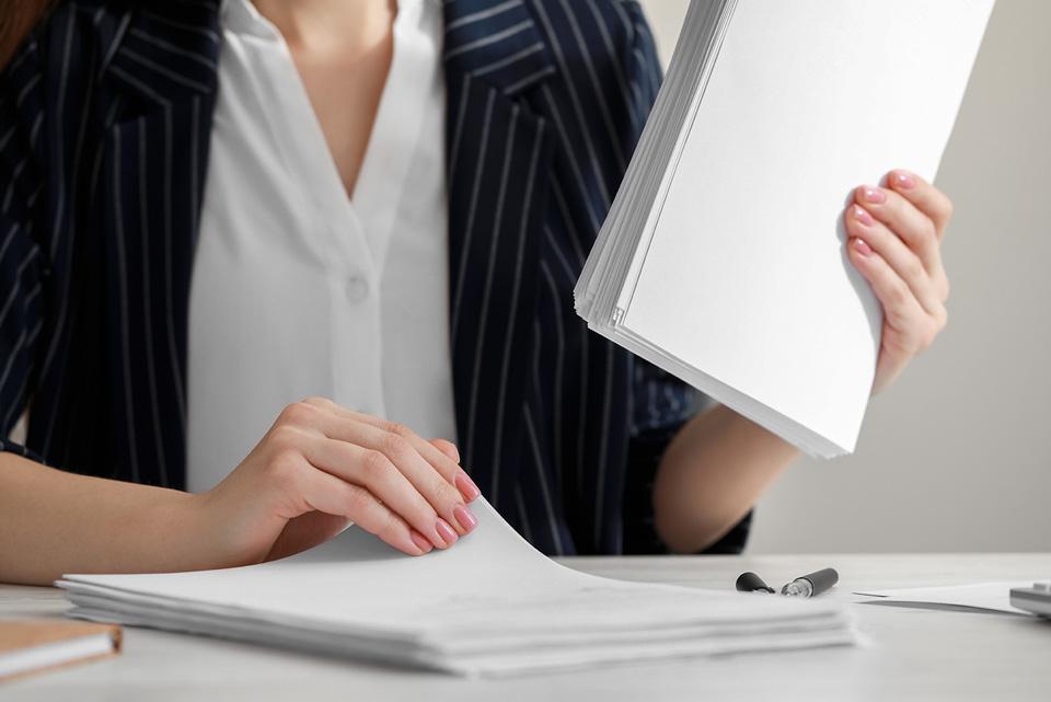 Businesswoman reading while holding a stack of paper